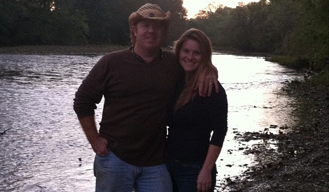 Owner and Co-Owner standing in nature, with a stream behind them.